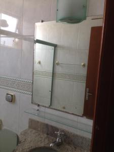 a bathroom with a mirror and a sink at Aconchego bem localizado in Varginha