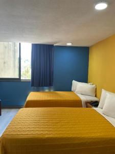 2 camas en una habitación con paredes azules y amarillas en Hotel Renovación, en Caracas