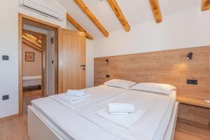 una camera da letto con un grande letto bianco con due asciugamani sopra di Casa del sol a Južni Škugori Altre 40 foto