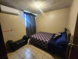 um quarto com uma cama e uma cadeira em Departamento 2 Recamaras 1 Baño Cocina y sala em Matamoros
