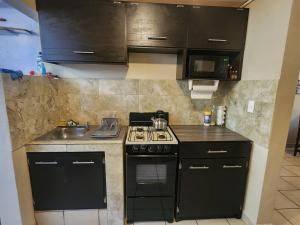 uma cozinha com armários pretos, um fogão e um lavatório em Departamento 2 Recamaras 1 Baño Cocina y sala em Matamoros