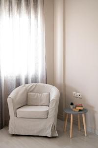 białe krzesło siedzące obok okna ze stołem w obiekcie Verkon Villas seaview senses w mieście Agia Pelagia
