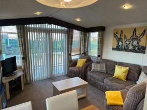 a living room with two couches and a tv at 8 berth pet friendly caravan Lyons Robin Hood in Meliden