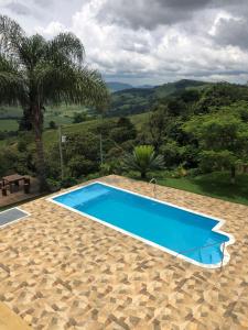 a blue swimming pool with a view of the mountains at Sítio Chalé 3Ipes in Senador José Bento
