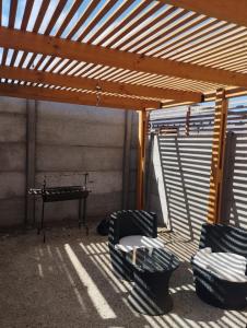 a patio with chairs and a table and a wooden pergola at Acogedora y Central Casa in La Serena