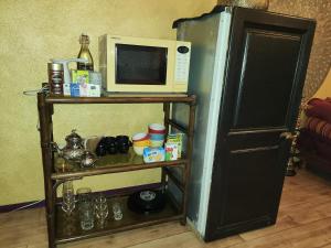 - un four micro-ondes installé au-dessus d'une étagère à côté d'un réfrigérateur dans l'établissement Chez Pipo, à Conthey