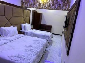 Cette chambre d'hôtel comprend 2 lits avec des draps blancs. dans l'établissement Defence Orchard DHA Karachi, à Karachi