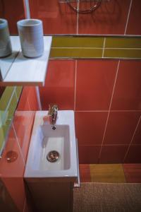 baño con lavabo blanco y azulejos rojos en Cabana Bendis en Rîşnov