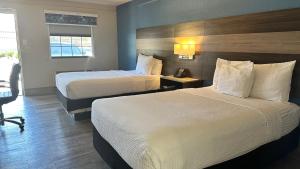 a hotel room with two beds and a desk at Days Inn by Wyndham San Diego Vista in Vista