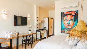 een slaapkamer met een bed, een bureau en een schilderij bij La Puesta Sayulita in Sayulita