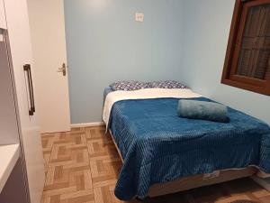 Un dormitorio con una cama con una manta azul. en Casa na Serra Gaucha Canela en Canela