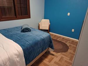 a bedroom with a bed with a blue blanket and a chair at Casa na Serra Gaucha Canela in Canela