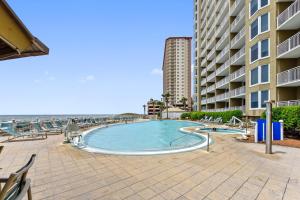 a swimming pool next to a building and the ocean at Emerald Beach #1227 by Book That Condo in Panama City Beach