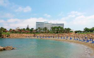 a beach with chairs and a building in the background at Crystal Springs Beach Hotel in Protaras