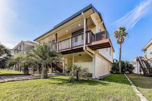 uma grande casa com varanda e palmeiras em Isla Bonita em Galveston