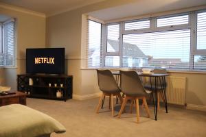 a room with a table and chairs and a television at Coastal Retreat - Brighton - Near the Beach in Peacehaven