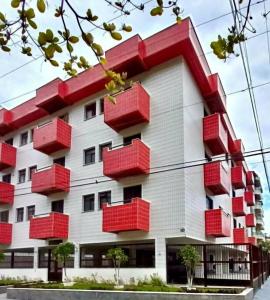ein Gebäude mit roten Balkonen an der Seite in der Unterkunft Apto23 pérola - Nº 201 - A 150m Praia Grande in Ubatuba