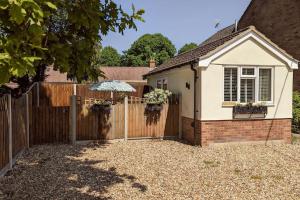 a house with a wooden fence and an umbrella at Oak Tree View - relax, reconnect, explore or work in East Harling