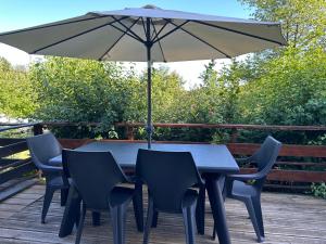 a table and chairs under an umbrella on a deck at Le petit Rabais in Virton