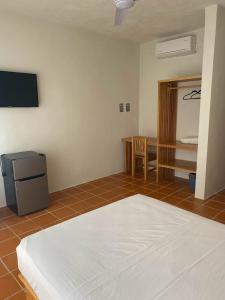 a room with a bed and a tv and a table at Hotel Bungalows Acuario in Puerto Escondido