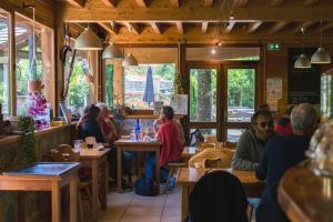 un grupo de personas sentadas en mesas en un restaurante en Hostel Quartier Libre en Saint-Jean-en-Royans