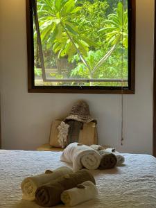 1 dormitorio con toallas en una cama con ventana en Feeling Trees Jungle Lodge en Cabuya