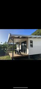 uma casa com um alpendre com duas mesas de piquenique em Tiny House Moorea Hinavai em Papetoai