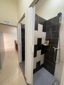 a bathroom with a shower with black and white tiles at Ommi Hostel in St Julian's