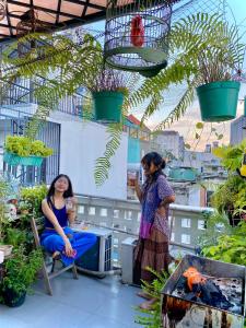 two women sitting on a balcony talking to each other at Laca Hostel in Ho Chi Minh City