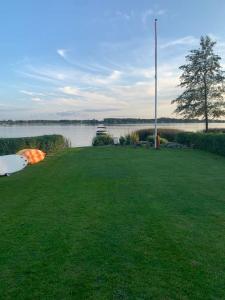 a grassy yard next to a body of water at Huset ved søen tæt på Herning og MCH og boxen 90 m2 in Sunds