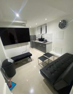 un salon avec un canapé noir et une cuisine dans l'établissement Appartement jolie Clichy, à Clichy-sous-Bois