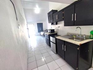 eine Küche mit schwarzen Schränken und weißem Fliesenboden in der Unterkunft Área Consulado y CAS 1 persona - D8 in Nuevo Laredo