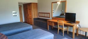 a hotel room with a desk and a bed and a mirror at Distinction Mackenzie Country Hotel in Twizel