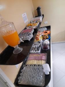 a buffet with a glass of orange juice and food at Hotel Dalias in Guarulhos