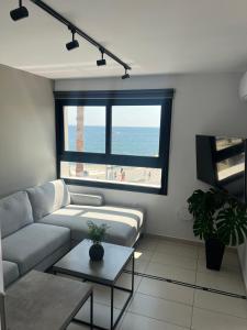 a living room with a couch and a view of the beach at Sea La Vie #1 - Luxury Seaview apartment in Paphos