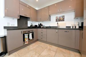 una cocina con electrodomésticos de acero inoxidable y armarios marrones en Bright Amelia Lodge - 2 bed 1 bath with WIFI and Netflix in the heart of London en Londres