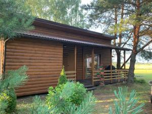 uma cabana de madeira com um alpendre e árvores em Pociunai relax house em Pociūnai