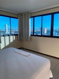 białe łóżko w pokoju z dużymi oknami w obiekcie Águas Palace Hotel w mieście Petrolina
