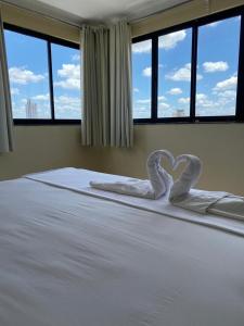 a bed with two swans making a heart on it at Águas Palace Hotel in Petrolina