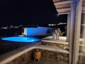 una estatua de un elefante junto a una piscina por la noche en Diamond Of Mykonos, en Ano Mera