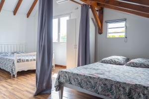 1 dormitorio con 2 camas y ventana en Villa Le Boursoie, villa au calme avec jacuzzis., en Les Abymes
