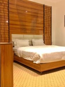 a bedroom with a large bed with a wooden headboard at مكان ينبع الجديد للشقق الفندقية in Yanbu