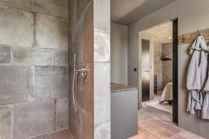a bathroom with a shower and a stone wall at Hvoll Villa in Ölfus +11 photos