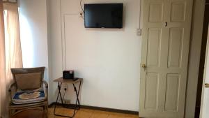 a room with a door and a chair and a television on a wall at Hostal del Prado in Temuco