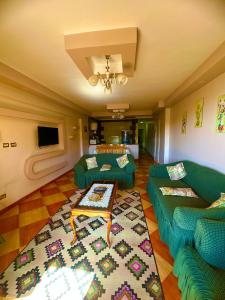 a living room with two green couches and a rug at Clara Apartment in Alexandria