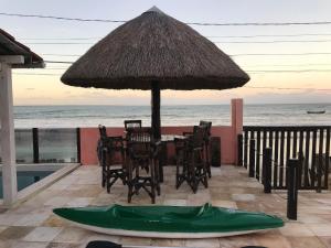 een tafel met stoelen en een parasol en een groene boot bij B&B Beach House Pousada Exclusiva pés na água Pontal do Peba única em Alagoas in Pontal do Peba