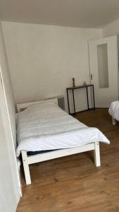 uma cama branca num quarto com piso em madeira em Appartement cœur de ville em Châtillon-sur-Indre