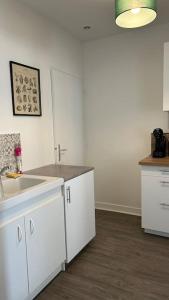 eine Küche mit weißen Schränken und einem Waschbecken in der Unterkunft Appartement cœur de ville in Châtillon-sur-Indre