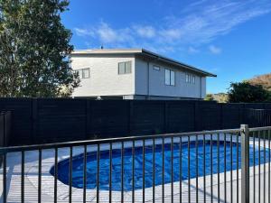 a fence around a swimming pool in front of a house at Ohope Villas with Spa,Sauna,Pool, Adults Only in Ohope Beach
