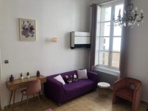 a living room with a purple couch and a window at Studio au cœur d'Avignon intra-muros in Avignon